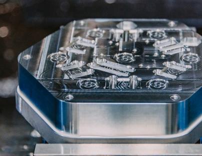 Aluminum piece cut into a hexagon shape with various etched designs on the surface